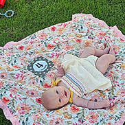 Elodie joined the competition — help win amazing prizes! baby, infant, blanket, floral_pattern, grass, outdoor, smiling, milestone_card, four_months, dress, cute, pacifier, red_cup, summer, relaxing, lying_down, child, nature, happy, portrait