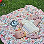 baby, infant, blanket, floral_pattern, grass, outdoor, smiling, milestone_card, four_months, dress, cute, pacifier, red_cup, summer, relaxing, lying_down, child, nature, happy, portrait