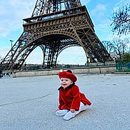 Aria participe au concours pour gagner de l'argent avec cette photo : baby, red_coat, red_beret, eiffel_tower, outdoor, sky, cloud, concrete, happy, child, tourist_spot, landmark, architecture, smile, winter_clothing, trees, person, sitting, urban, daytime