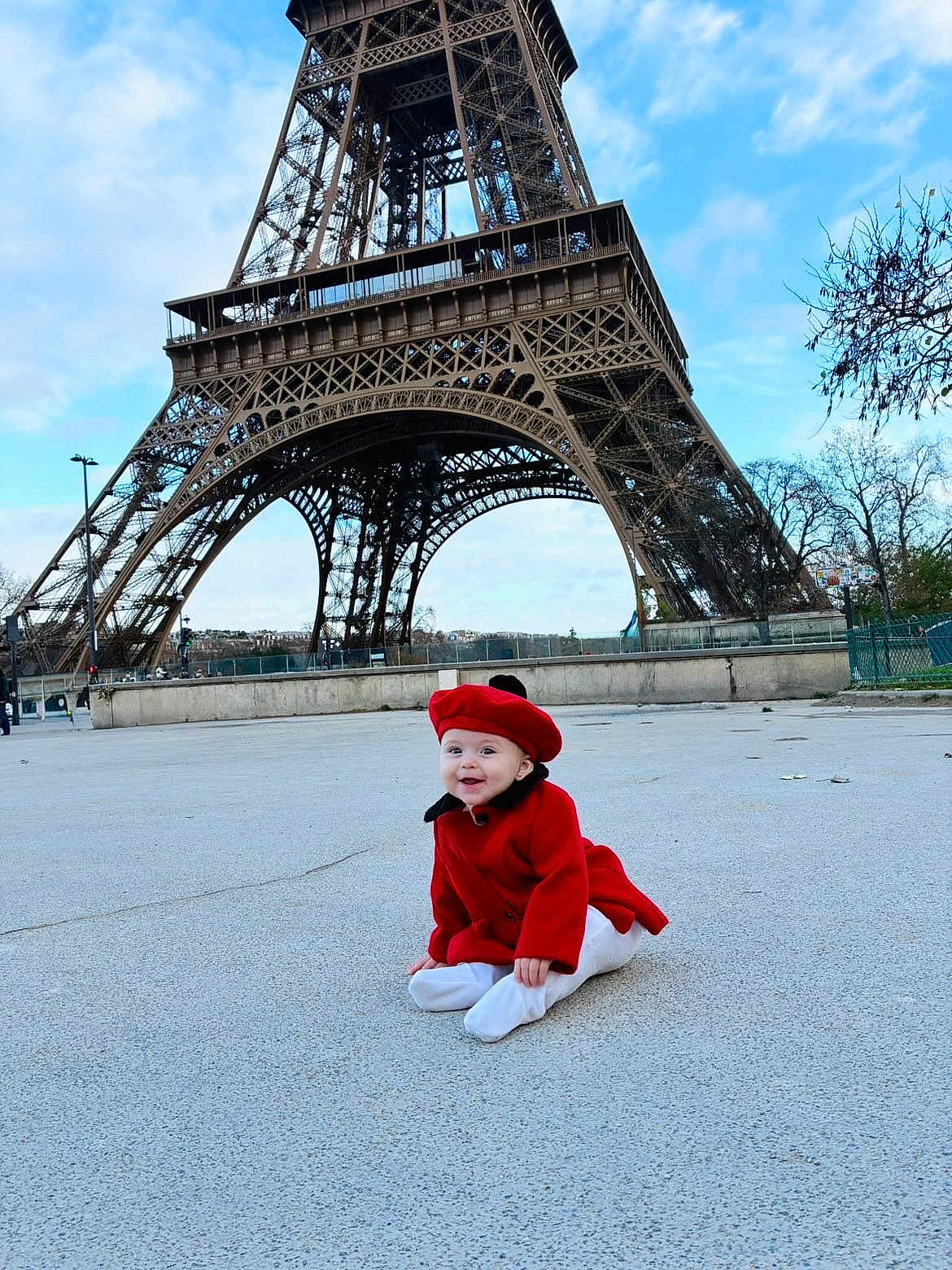 Aria participe au concours pour gagner de l'argent avec cette photo : baby, red_coat, red_beret, eiffel_tower, outdoor, sky, cloud, concrete, happy, child, tourist_spot, landmark, architecture, smile, winter_clothing, trees, person, sitting, urban, daytime