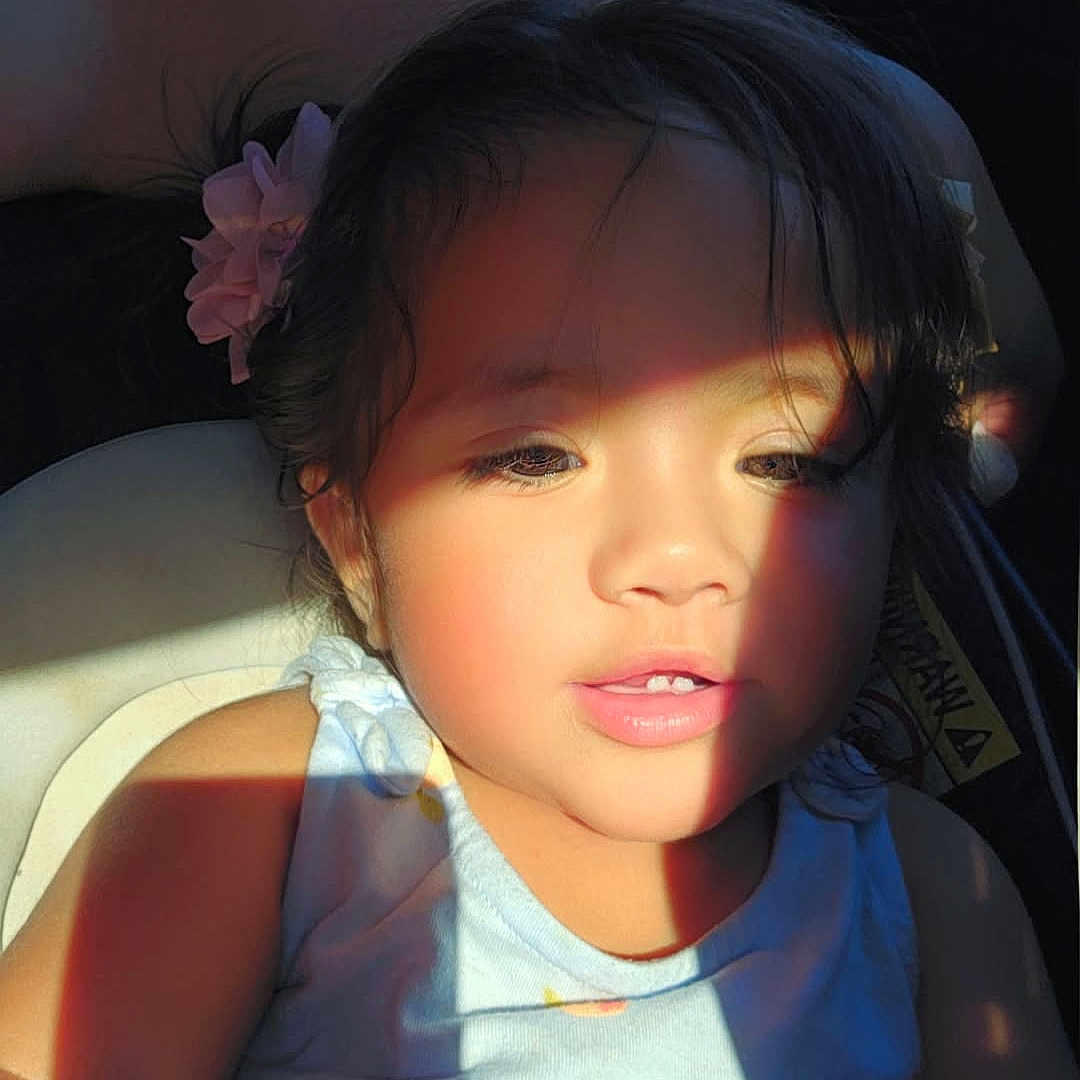 Desi joined the competition — help win amazing prizes! child, girl, toddler, portrait, car, car_interior, sitting, sunlight, sunbeam, face, hair_clip, flower, dress, blue_clothing, smiling, indoors, vehicle, seat, passenger, natural_light