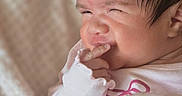 Desi joined the competition — help win amazing prizes! newborn, baby, infant, portrait, face, finger, hand, pink_clothing, blanket, cozy, indoors, close_up, dark_hair, sleepy, squinting, cute, gentle, soft_lighting, infant_hand, nursery