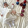 Charlotte participe au concours pour gagner de l'argent avec cette photo : baby, infant, blanket, plush, toy, bunny, doll, christmas_ornaments, red, blue, pink, white_clothing, headband, pacifier, socks, lying_down, soft_texture, festive, holiday, cute