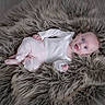 Lila is registered to the contest to win money with this photo: baby, infant, lying_down, fluffy_rug, soft_texture, pastel_clothing, blue_eyes, indoor, cozy, cute, child, portrait, flooring, expression, head, skin, small_hands, relaxed, comfort, casual