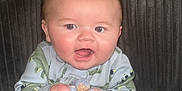 Dawson is registered to the contest to win money with this photo: animal_print, baby, blanket, blue_blanket, clothing, couch, cozy, face, furniture, happy, head, indoor, infant, person, plush, portrait, sitting, smile, wood_paneling, young_child