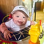 baby, bright_colors, cheerful, child, chubby_cheeks, clothing, cute, face, happy, headwear, indoor, infant, person, plastic_toy, play_seat, seat, smiling, toy, white_cap, young_child