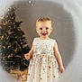 toddler, child, smiling, dress, sparkling, christmas_tree, lights, holiday, winter, frosted_window, joyful, indoor, portrait, festive, cute, holiday_season, happy, young_child, celebration, decorations