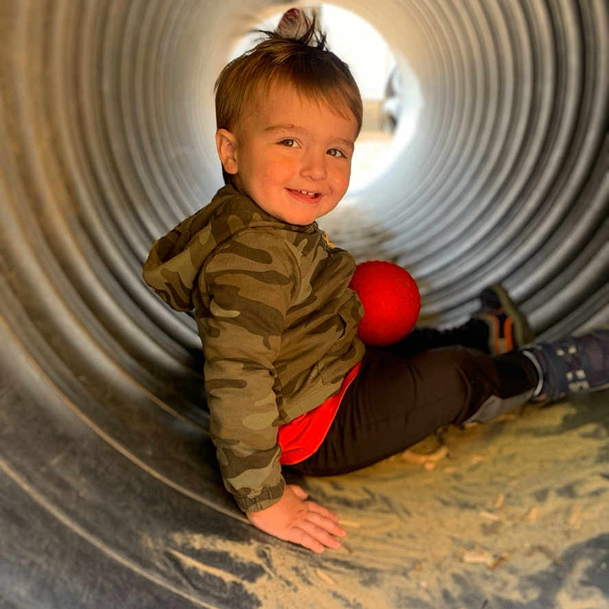 Jameson is registered to the contest to win money with this photo: baby, bodypart, clothing, face, finger, footwear, hand, head, outdoorplayarea, outdoors, pants, person, photography, playarea, portrait, shoe, slide, sphere, toy, tunnel