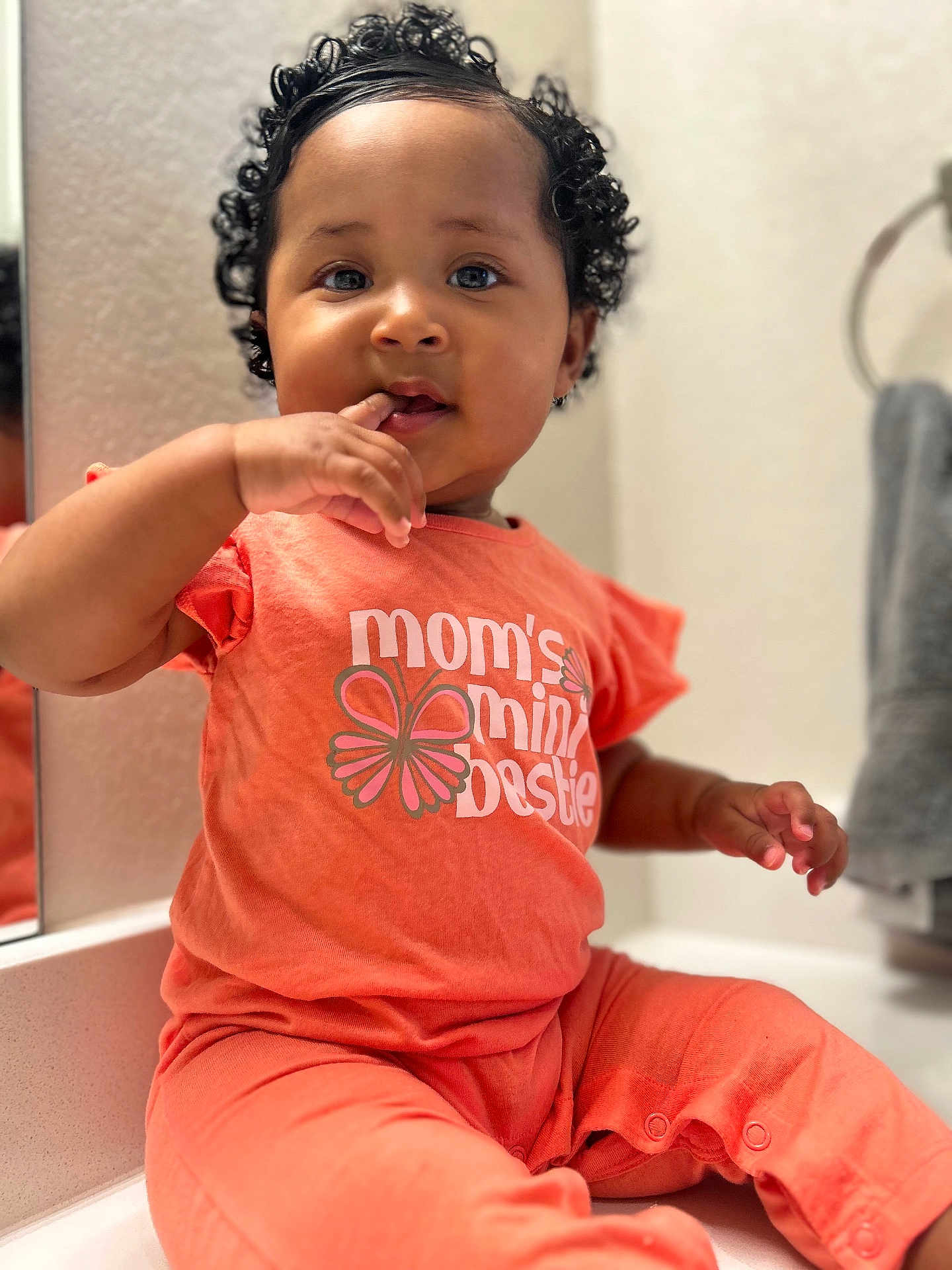 Love joined the competition — help win amazing prizes! baby, bright_colors, casual, child, closeup, countertop, curly_hair, cute, expression, finger_in_mouth, indoor, infant, mirror, orange_clothing, person, portrait, reflection, short_sleeves, sitting, toddler