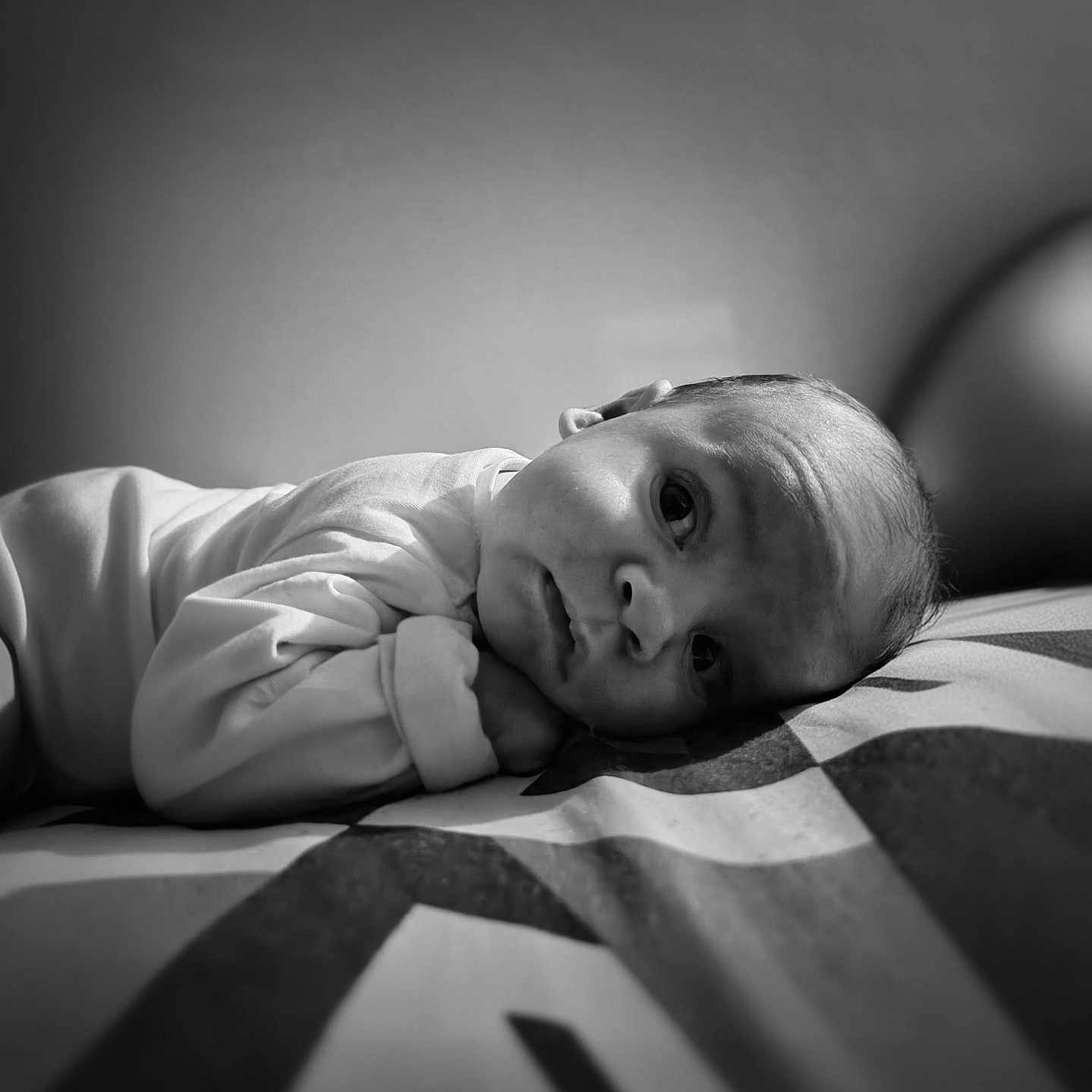 Iliano a rejoint le concours — aidez-le/la à gagner de superbes lots ! baby, black_and_white, close_up, clothing, cute, expression, eyes, face, head, indoor, infant, lying_down, newborn, patterned_bed, peaceful, person, portrait, skin, soft_lighting, young_child