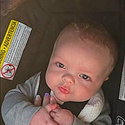 James joined the competition — help win amazing prizes! baby, infant, car_seat, hand, holding, child, cute, face, skin, clothing, seat, safety_label, person, young, looking, expression, indoor, human, childhood, toddler
