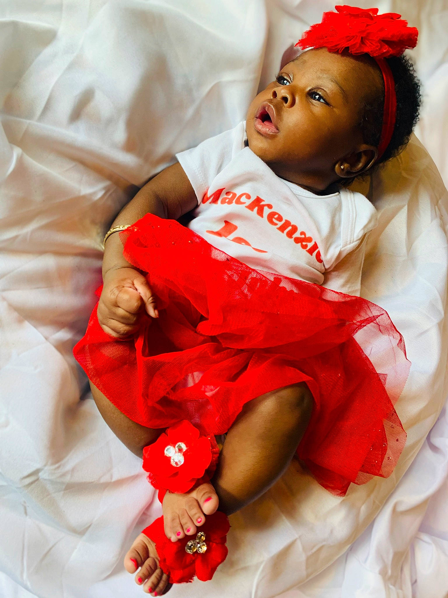 Mackenzie is registered to the contest to win money with this photo: baby, baby_toddler_clothing, carmine, child, comfort, event, face, finger, gesture, glove, hand, happy, head, person, pink, red, skin, sleeve, thigh, toddler