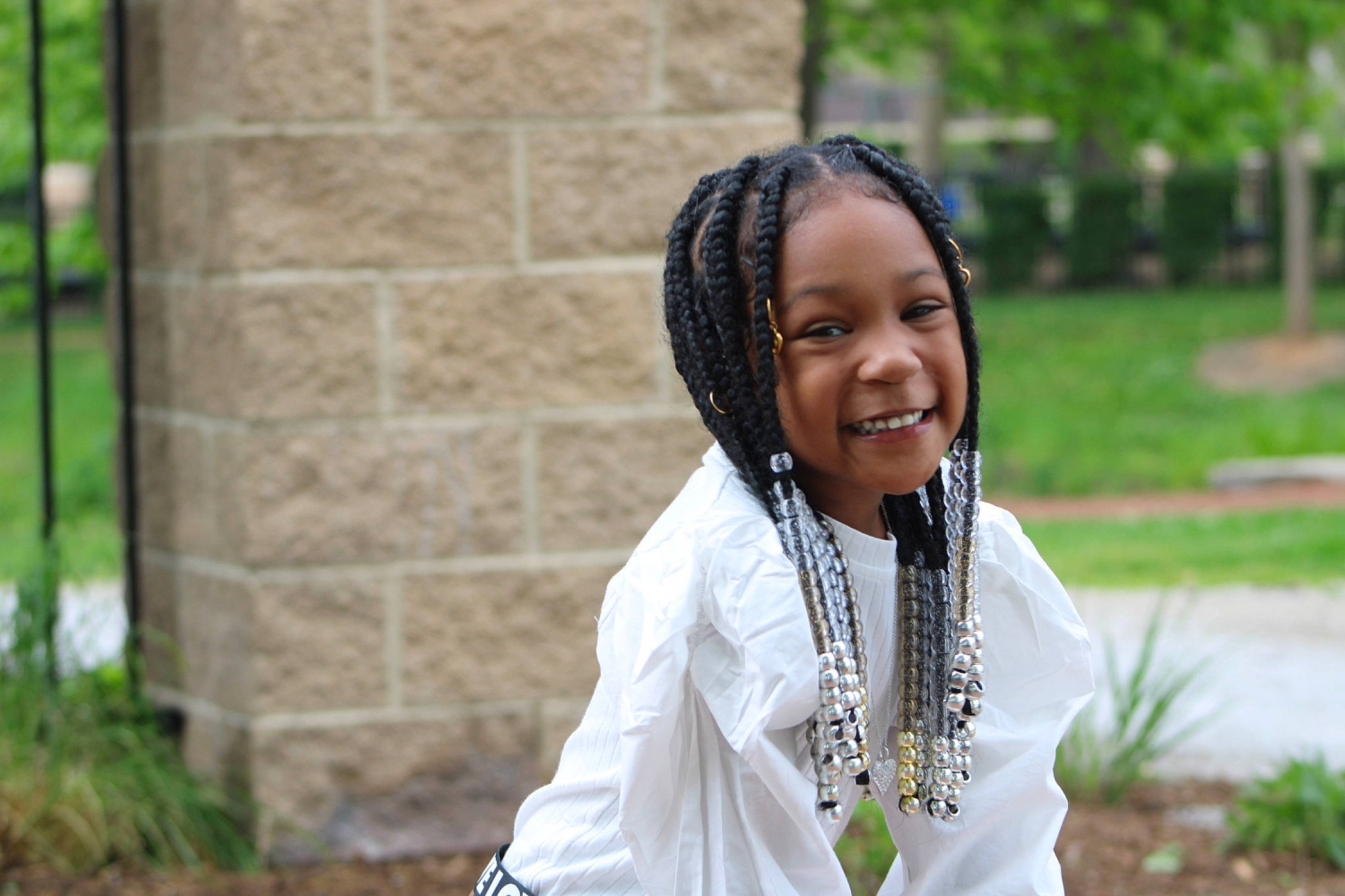 Kira is registered to the contest to win money with this photo: black_hair, braid, child, event, eye, fashion_accessory, fun, grass, happy, jewellery, joy, leisure, necklace, people_in_nature, person, plant, recreation, smile, street_fashion, toddler