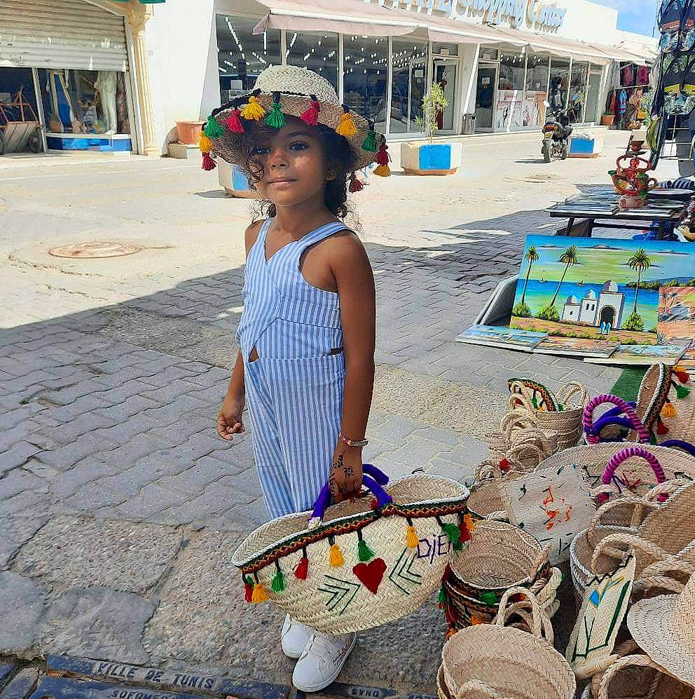 Aicha participe au concours pour gagner de l'argent avec cette photo : bag, basket, child, event, hat, hawker, headwear, human_settlement, leisure, luggage_and_bags, market, person, photograph, public_space, sidewalk, snapshot, storage_basket, summer, temple, textile