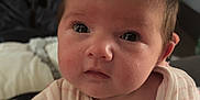 Hallie is registered to the contest to win money with this photo: baby, infant, face, eyes, hands, clothing, onesie, indoor, blanket, furniture, person, portrait, cute, newborn, skin, expression, head, sitting, soft, young