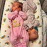 baby, infant, pacifier, pink_clothing, floral_clothing, cushion, rainbow_pattern, stars_pattern, lying_down, sleepwear, bedroom, soft_toys, newborn, cute, twin_babies, face, head, hands, blanket, cozy