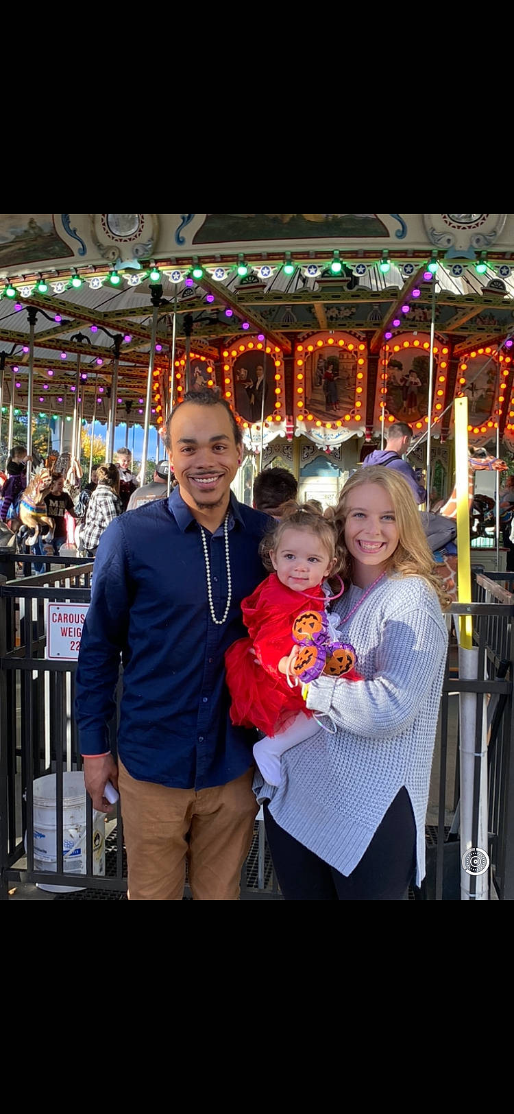 Laurel is registered to the contest to win money with this photo: amusement_park, amusement_ride, carousel, child, event, fair, fence, festival, fun, happy, holiday, joy, leisure, nonbuilding_structure, person, public_event, recreation, smile, t_shirt, toddler