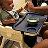 Genesis joined the competition — help win amazing prizes! baby, high_chair, feeding, spoon, bib, food, bowl, tattoo, arm, person, indoor, table, chair, child, infant, meal, dining, cute, curious, home