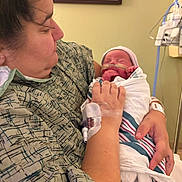 Alaysia is registered to the contest to win money with this photo: mother, newborn, baby, hospital, medical_equipment, blanket, gown, infant, person, holding, care, love, healthcare, patient, bedroom, face, hand, hospital_room, wrapped, rest