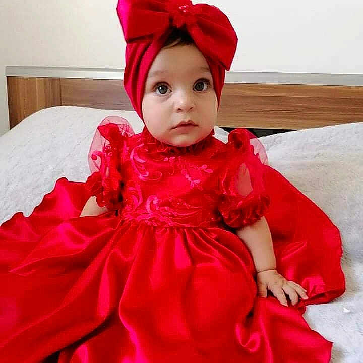 Elisa a rejoint le concours — aidez-le/la à gagner de superbes lots ! baby, child, red_dress, headband, bow, sitting, bed, indoors, portrait, cute, infant, clothing, fabric, face, eyes, hands, young_child, fancy, dress, curious