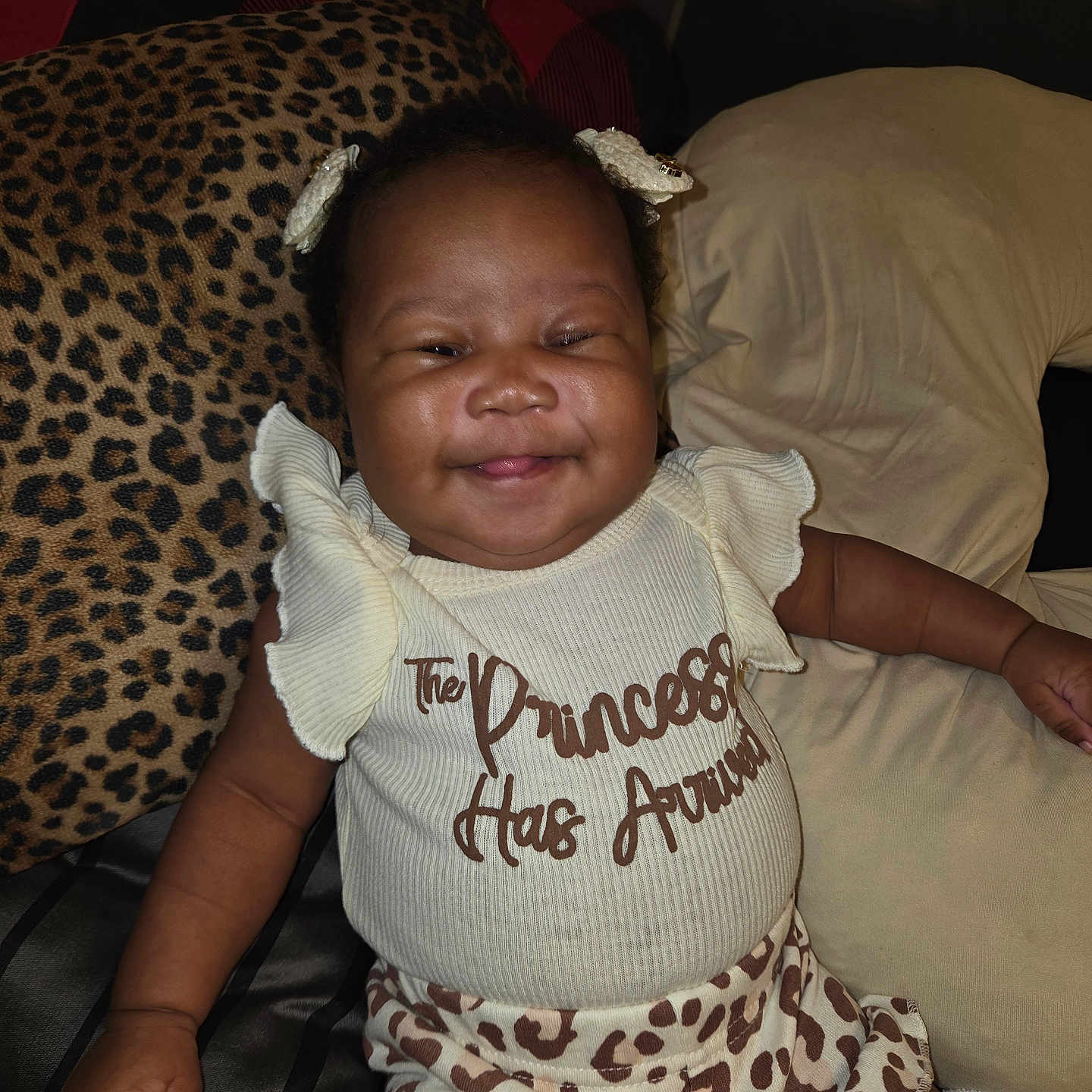 Teliyah is registered to the contest to win money with this photo: baby, smiling, girl, infant, cute, clothing, pillow, couch, indoor, happy, portrait, child, pattern, leopard_print, text, relaxed, sitting, home, person, fashion