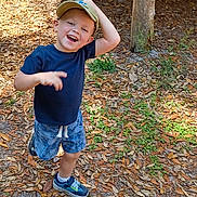 David Leland joined the competition — help win amazing prizes! child, boy, smiling, cap, shorts, sneakers, outdoor, forest, leaves, sunlight, happy, playful, nature, person, casual_clothing, daylight, tree_trunks, ground, greenery, young