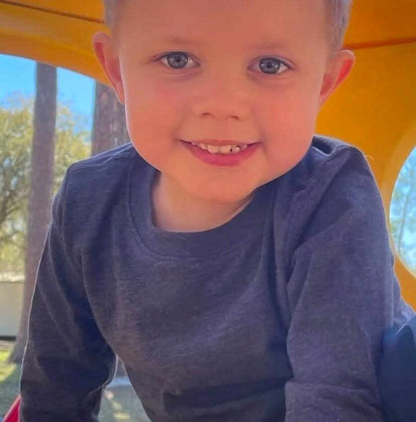 David Leland is registered to the contest to win money with this photo: child, smiling, face, blue_eyes, long_sleeve_shirt, playground, yellow_play_structure, outdoor, trees, daylight, happy, boy, casual_clothing, closeup, portrait, young_child, cute, fun, park, play