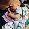 baby, child, infant, sleeping, blanket, footprints, person, young_person, holding, cuddle, tenderness, love, indoor, plaid_chair, pacifier, striped_shirt, close_up, portrait, family, care