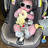 baby, car_seat, sunglasses, plush_toy, infant, socks, seatbelt, toy, child, indoor, cute, person, chicco, warning_label, car_seat_accessory, floor, head_support, baby_clothing, seat, baby_toy