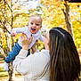 baby, child, infant, adult, parent, park, outdoor, autumn, fall_foliage, tree, leaves, smile, happy, holding, lift, sweater, jeans, portrait, hair, playful