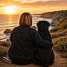 Ohana participe au concours pour gagner de l'argent avec cette photo : person, dog, sunset, ocean, cliff, nature, outdoor, landscape, companionship, pet, animal, human, scenic, relaxation, grass, rocks, sky, clouds, casual_clothing, back_view