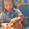 Ti Belle participe au concours pour gagner de l'argent avec cette photo : blue_background, casual_clothing, child, close_up, companionship, couch, curly_hair, cute, denim_overall, dog, gentle_touch, hand, happy_pet, indoor, patterned_fabric, pet, smiling_dog, tongue_out, warm_light, young_child