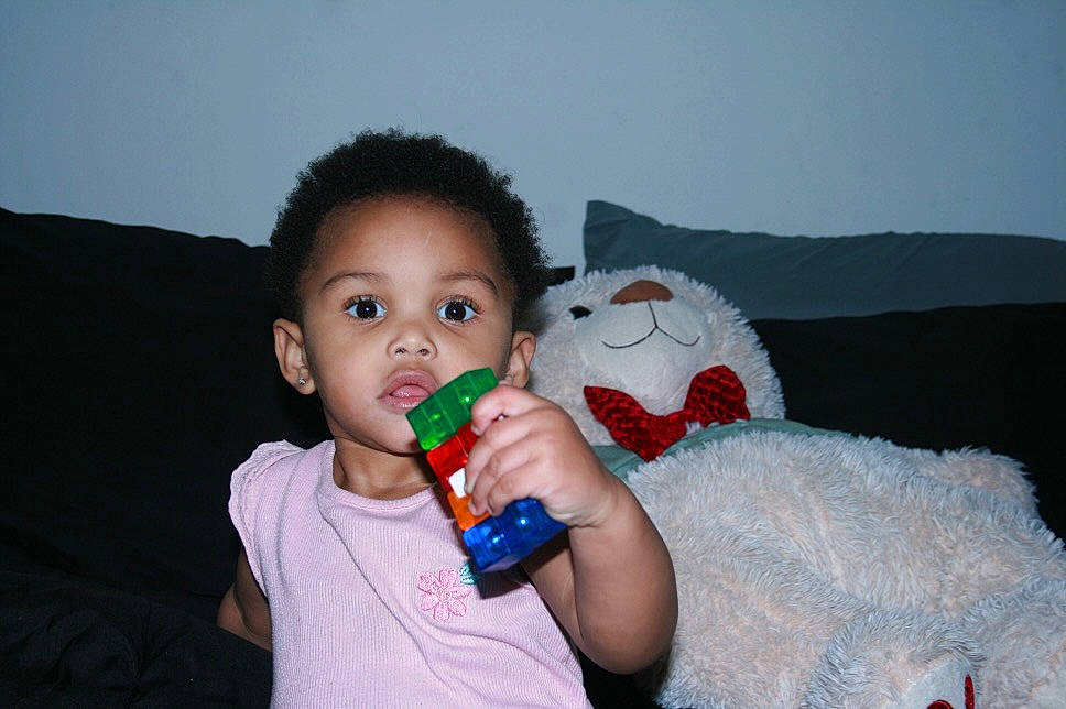 Kimani is registered to the contest to win money with this photo: arm, baby_toddler_clothing, cheek, child, facial_expression, finger, fun, gesture, happy, head, iris, mouth, nail, nose, person, skin, sleeve, stuffed_toy, thumb, toddler