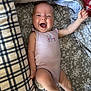 baby, infant, smiling, happy, onesie, blanket, patterned_blanket, lying_down, arm_up, barefoot, portrait, cute, child, young_child, indoor, fabric, plaid_blanket, floral_pattern, skin, person