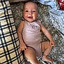 baby, infant, smiling, lying_down, onesie, blanket, floral_pattern, plaid, cozy, comfort, happy, cute, skin, face, arm, leg, indoors, child, person, soft