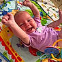 baby, infant, smiling, purple_onesie, play_mat, colorful, toy, happy, arms_up, lying_down, indoor, floor, cute, child, face, expression, joy, animal_print, soft_toy, patterned