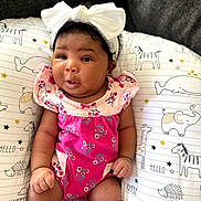 Yara is registered to the contest to win money with this photo: baby, infant, child, headband, bow, pink_clothing, floral_pattern, cushion, animal_print, elephant, giraffe, whale, hedgehog, happy_baby_text, hello_text, cute, indoors, portrait, sitting, soft_lighting