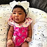 baby, infant, child, headband, bow, pink_clothing, floral_pattern, cushion, animal_print, elephant, giraffe, whale, hedgehog, happy_baby_text, hello_text, cute, indoors, portrait, sitting, soft_lighting