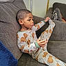 Ziyan is registered to the contest to win money with this photo: child, pajamas, couch, indoor, stretching, bear_pattern, relaxed, home, furniture, person, cozy, comfort, seated, casual, portrait, young_child, sleepwear, living_room, thoughtful, cute