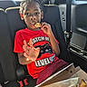 Ziyan joined the competition — help win amazing prizes! child, boy, car, backseat, pizza, food, eating, red_shirt, seatbelt, window, sunlight, casual, snack, hand, face, person, interior, seat, young, relaxed