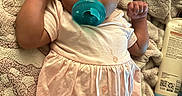 Ashai is registered to the contest to win money with this photo: baby, pacifier, blanket, dress, infant, child, skin, hand, face, lying_down, cloth, comfort, cute, newborn, indoors, relaxing, apparel, person, portrait, soft
