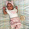 Ashai is registered to the contest to win money with this photo: baby, infant, newborn, headband, floral, pants, onesie, blanket, plaid, sign, one_month, lying_down, cute, sleepy, indoors, person, child, small, milestone, portrait
