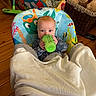 baby, bottle, blanket, baby_chair, colorful, indoor, wooden_floor, stuffed_animals, basket, clothing, child, person, face, blue_eyes, toy, floor, home, cozy, infant, seating
