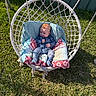 Theodore is registered to the contest to win money with this photo: baby, child, swing, chair, cushion, grass, outdoor, sunlight, blue_onesie, baby_clothing, infant, relaxing, daylight, woven_chair, play_area, green_grass, summer, cute, smiling, portrait