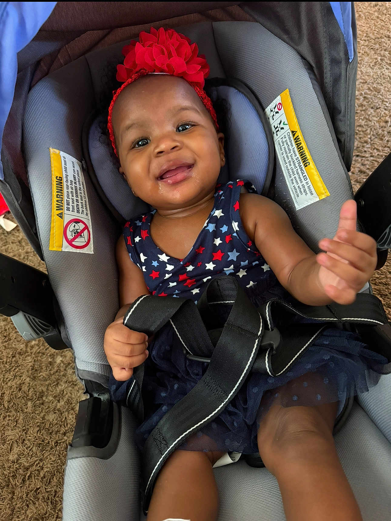 Dajiyah is registered to the contest to win money with this photo: baby, child, car_seat, headband, red_flower, dress, stars, smile, happy, infant, seatbelt, safety_straps, indoors, carrying_device, person, cute, toddler, clothing, face, skin
