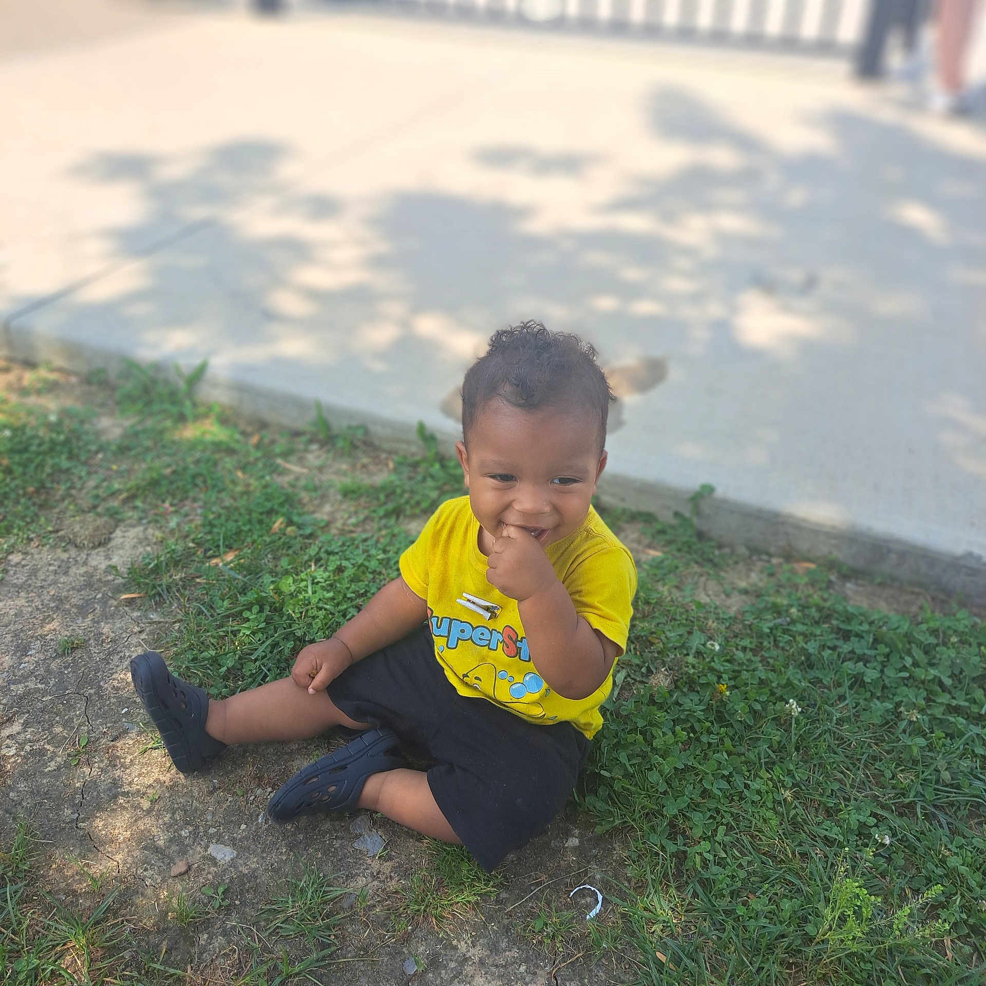 Phillip is registered to the contest to win money with this photo: bodypart, boy, child, clothing, face, finger, footwear, grass, hand, head, male, pants, person, photography, plant, portrait, shoe, shorts, sitting, t_shirt