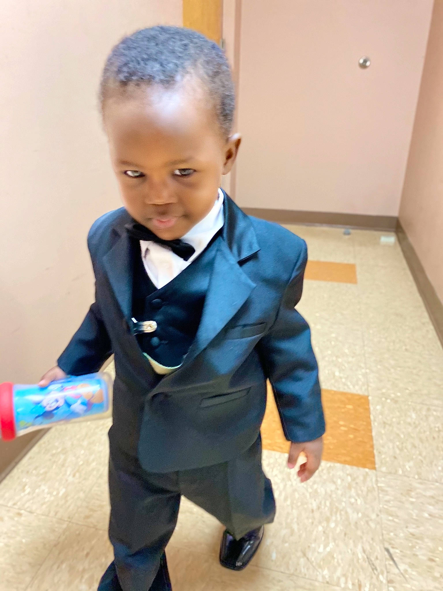 Micheal is registered to the contest to win money with this photo: baby_toddler_clothing, blazer, bow_tie, child, coat, collar, dress, dress_shirt, electric_blue, event, fashion_design, flooring, formal_wear, person, shoulder, sitting, sleeve, suit, tie, toddler