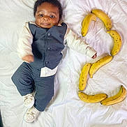 Naël a rejoint le concours — aidez-le/la à gagner de superbes lots ! baby, infant, child, suit, clothing, white_sheet, bananas, fruit, number_three, lying_down, smiling, cute, footwear, shoes, indoor, portrait, face, happy, young, playful