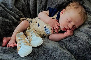 Korbyn is registered to the contest to win money with this photo: baby, baby_toddler_clothing, barefoot, bedtime, cheek, child, comfort, flooring, foot, fur, grass, human_leg, linens, nap, person, sitting, skin, sleeve, thumb, toddler