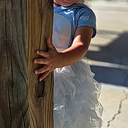 Kayleigh is registered to the contest to win money with this photo: child, girl, smiling, barefoot, tutu, blue_shirt, wooden_post, outdoor, sunlight, concrete, crack, playful, happy, portrait, young_child, daylight, grass, shadow, cute, standing